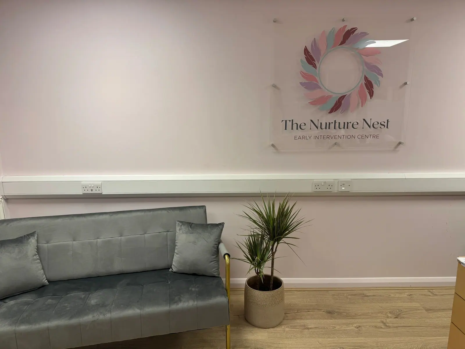 Reception waiting area with sofa and The Nurture Nest sign
